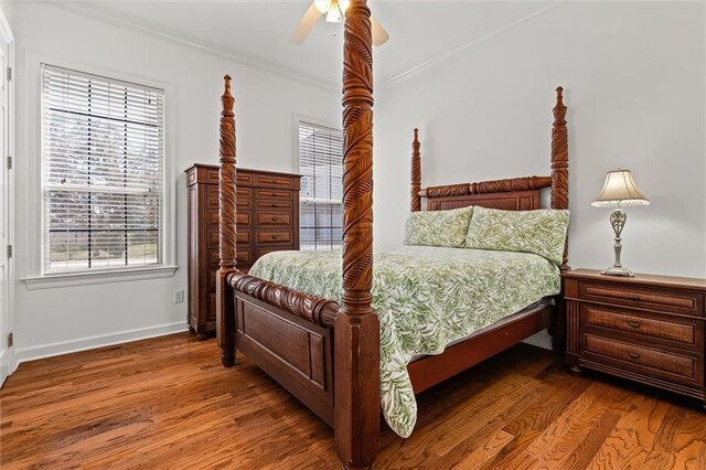 bedroom with a ceiling fan, crown molding, baseboards, and wood finished floors