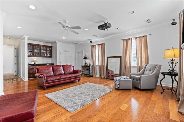 living area featuring visible vents, ornamental molding, recessed lighting, bar, and wood finished floors