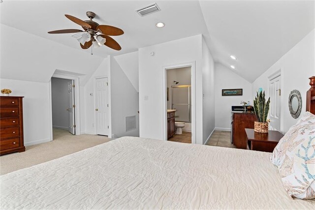 bedroom featuring visible vents, lofted ceiling, ensuite bath, and carpet flooring