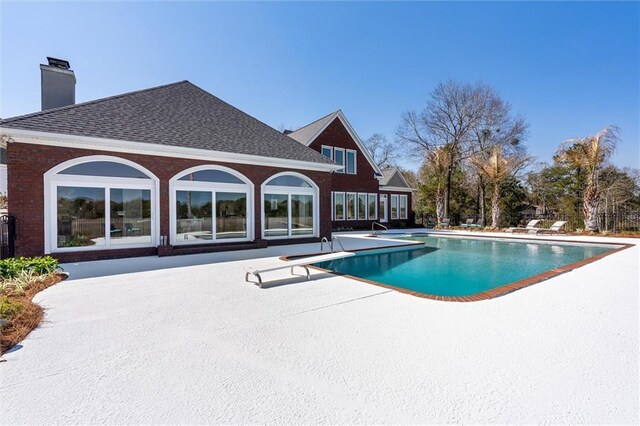 outdoor pool featuring a patio area and a diving board