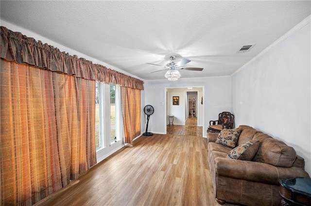 living room with crown molding, ceiling fan, a textured ceiling, and light hardwood / wood-style floors