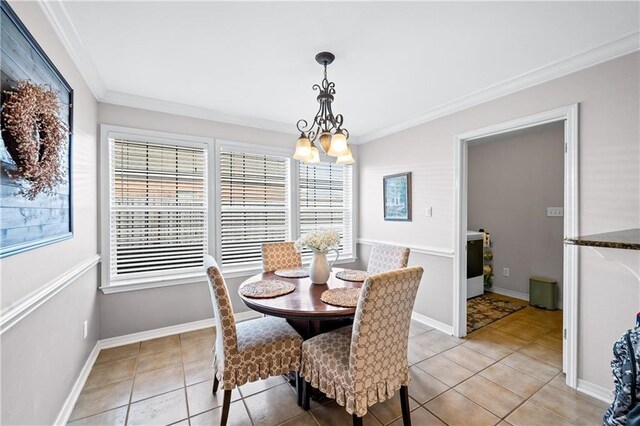 dining space featuring light tile patterned floors, crown molding, and an inviting chandelier