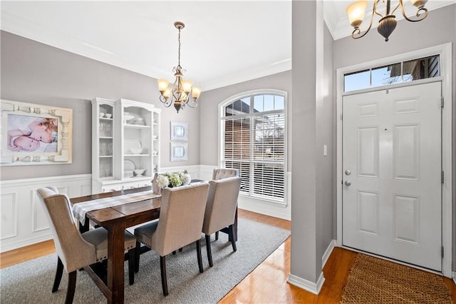 dining space with a notable chandelier, light wood-type flooring, and ornamental molding