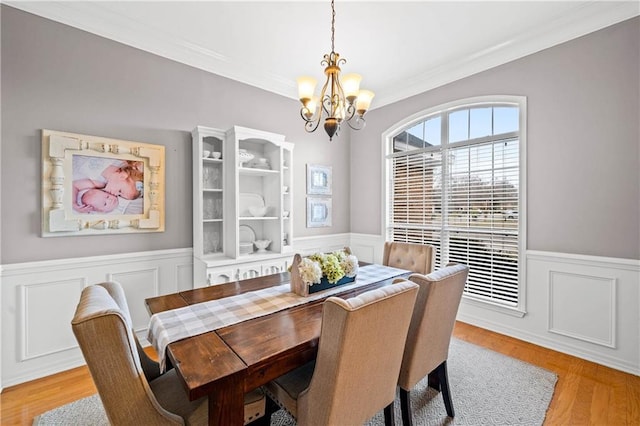 dining space featuring ornamental molding, light wood-type flooring, and a notable chandelier