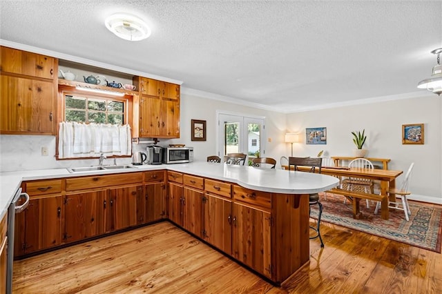 kitchen featuring a breakfast bar, sink, kitchen peninsula, light hardwood / wood-style flooring, and crown molding