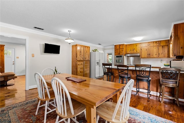 dining space with crown molding and dark wood-type flooring