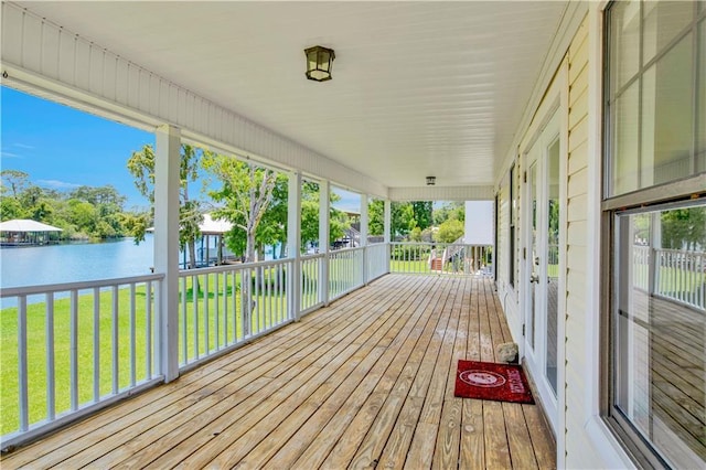 wooden deck featuring a yard, a water view, and covered porch