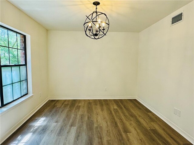 unfurnished room with a notable chandelier and hardwood / wood-style flooring