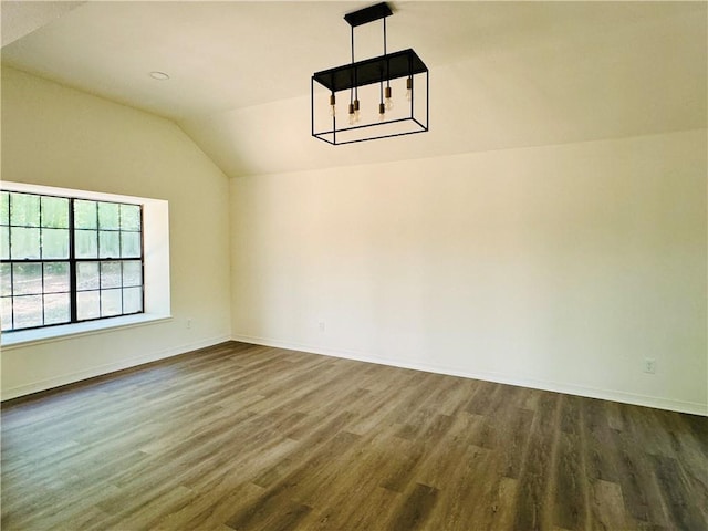 unfurnished room featuring lofted ceiling, a chandelier, and dark wood-type flooring