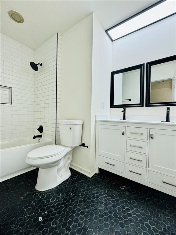 full bathroom with tile flooring, toilet, tiled shower / bath, and large vanity