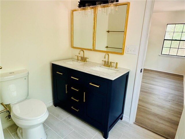 bathroom with double sink vanity, toilet, and wood-type flooring