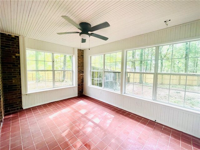 unfurnished sunroom with a healthy amount of sunlight, wood ceiling, and ceiling fan