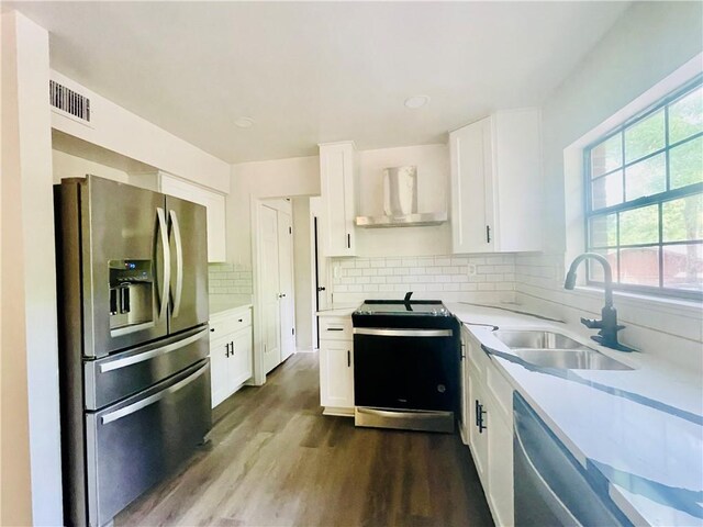 kitchen featuring stainless steel appliances, hardwood / wood-style floors, wall chimney exhaust hood, backsplash, and sink