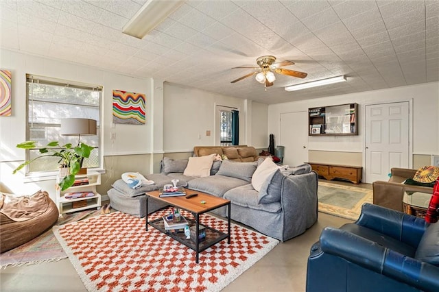 living room featuring finished concrete flooring and a ceiling fan