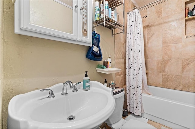 bathroom featuring toilet, shower / tub combo with curtain, and a sink