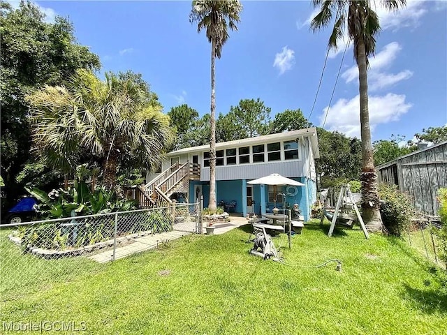 back of property featuring stairway, a yard, and a fenced backyard