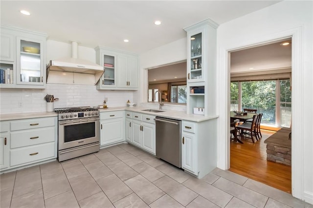 kitchen with sink, ventilation hood, appliances with stainless steel finishes, white cabinets, and light wood-type flooring