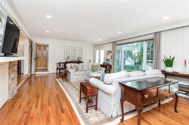 living room with ornamental molding, a fireplace, and light hardwood / wood-style flooring