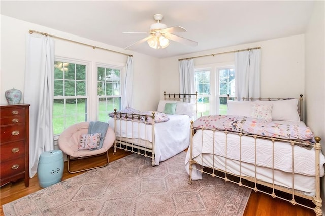 bedroom with ceiling fan, wood-type flooring, and multiple windows