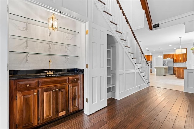 bar with hardwood / wood-style flooring, decorative backsplash, pendant lighting, and stainless steel fridge