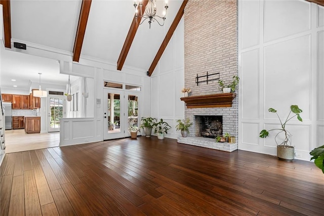 unfurnished living room featuring high vaulted ceiling, a fireplace, an inviting chandelier, and hardwood / wood-style flooring