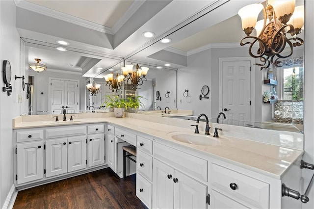 bathroom with vanity, a notable chandelier, ornamental molding, and hardwood / wood-style flooring