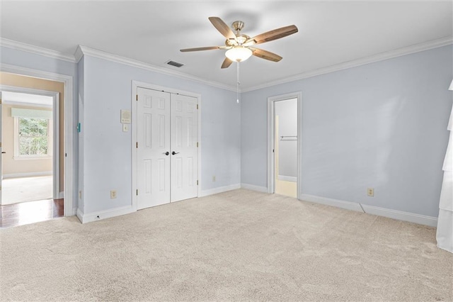 unfurnished bedroom featuring ceiling fan, light carpet, a closet, and ornamental molding