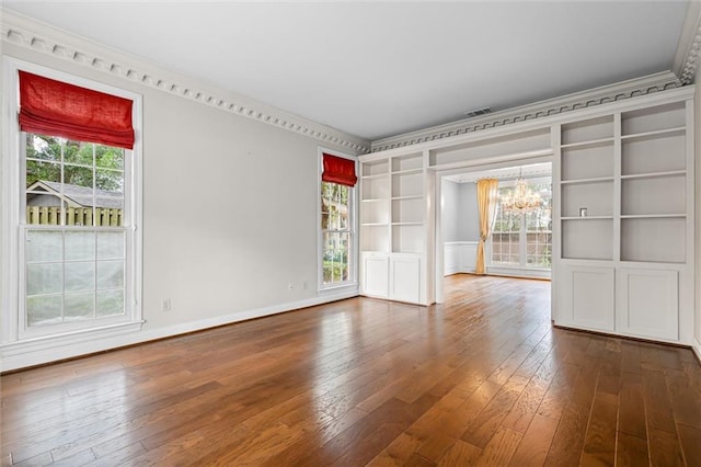 unfurnished room with a chandelier, built in features, hardwood / wood-style flooring, and ornamental molding