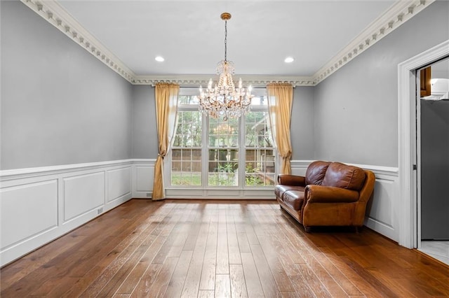 living area with an inviting chandelier, crown molding, and hardwood / wood-style floors