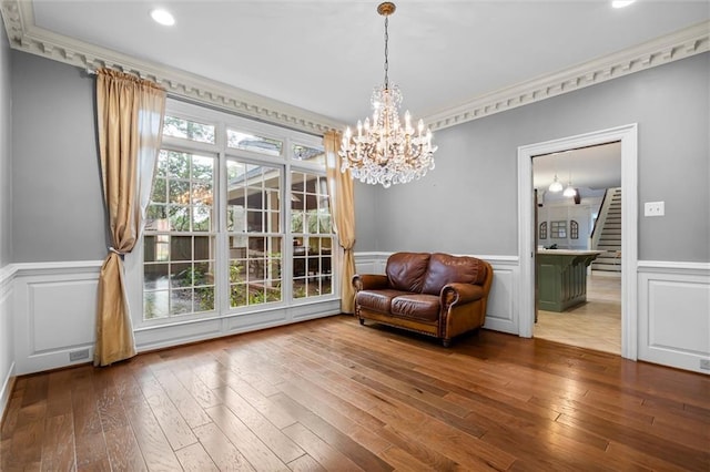 living area featuring an inviting chandelier, ornamental molding, and wood-type flooring