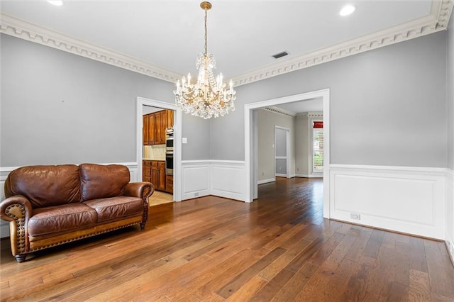 sitting room featuring dark hardwood / wood-style floors, ornamental molding, and a chandelier