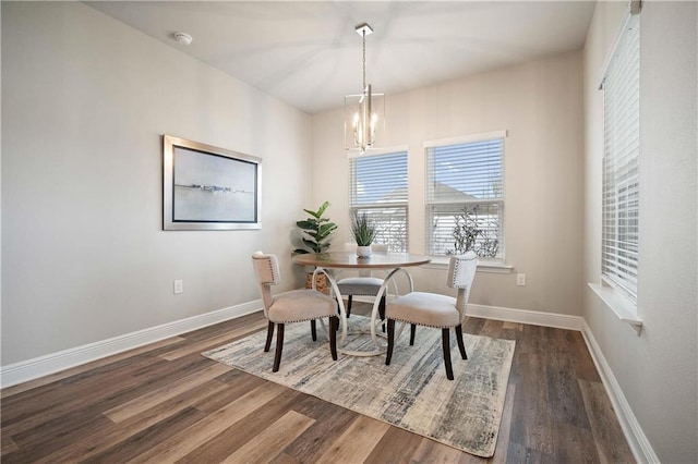 dining area with dark hardwood / wood-style flooring and an inviting chandelier