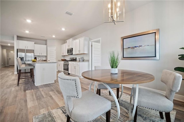 dining room with a chandelier, sink, and light hardwood / wood-style flooring