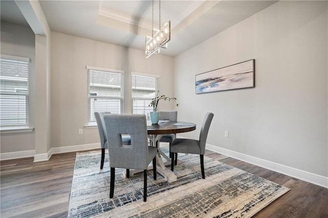 dining room featuring a chandelier, crown molding, dark wood-type flooring, and a tray ceiling