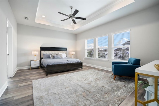 bedroom featuring a raised ceiling, ceiling fan, crown molding, and hardwood / wood-style flooring