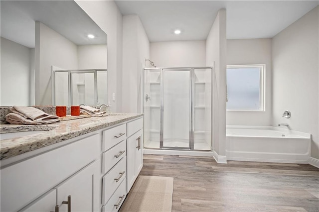 bathroom with plus walk in shower, wood-type flooring, and vanity