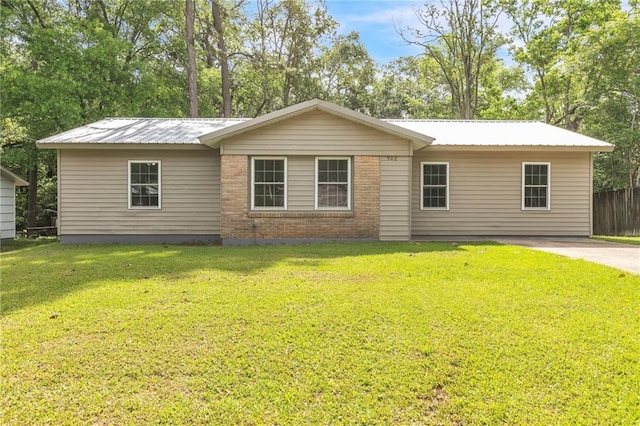 view of front of property with brick siding, a front lawn, metal roof, and fence