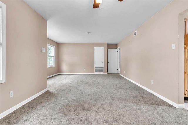 unfurnished room with visible vents, carpet flooring, baseboards, and ceiling fan