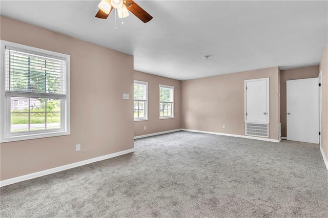 carpeted spare room featuring a ceiling fan and baseboards
