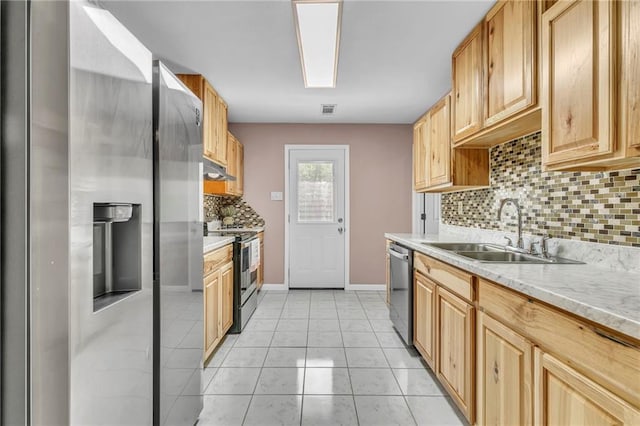 kitchen featuring stainless steel appliances, a sink, tasteful backsplash, visible vents, and baseboards