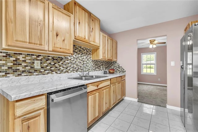 kitchen featuring light brown cabinetry, stainless steel appliances, light countertops, and a sink