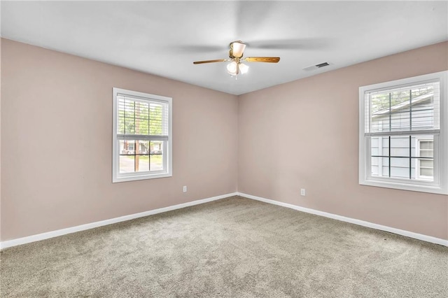 carpeted empty room with visible vents, a ceiling fan, and baseboards