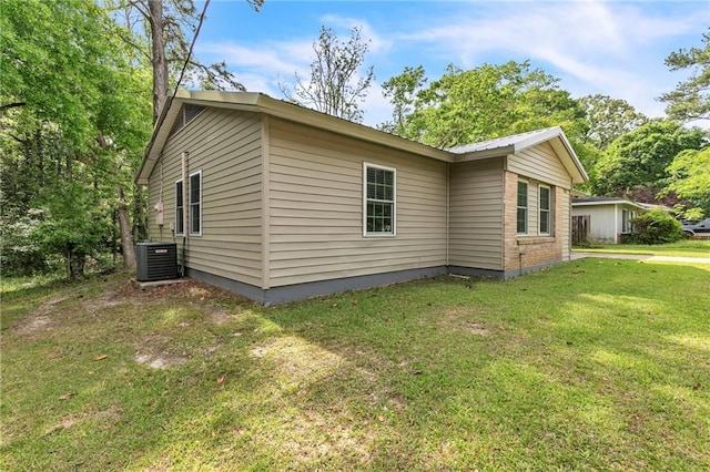 view of side of home featuring central AC unit and a yard