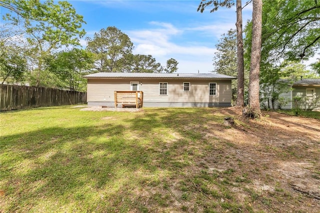rear view of house with fence, a lawn, and crawl space