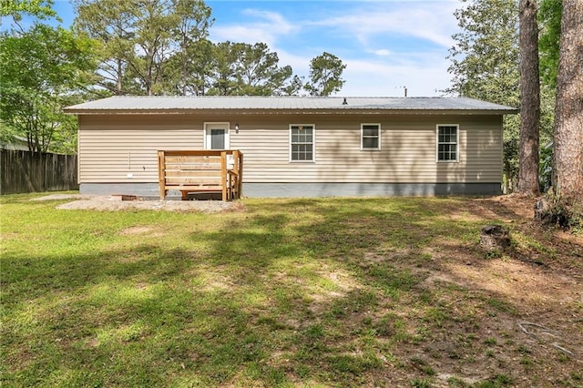 rear view of house featuring fence, a yard, and metal roof
