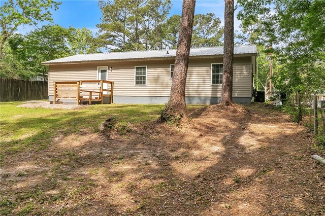 back of property featuring fence, a lawn, central air condition unit, and metal roof