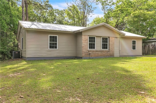 back of house featuring fence, a lawn, and metal roof