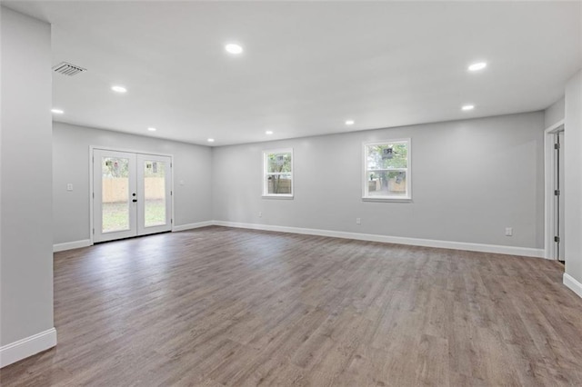 unfurnished room with a healthy amount of sunlight, hardwood / wood-style floors, and french doors