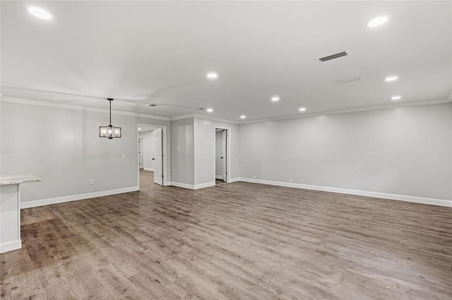 unfurnished living room featuring a chandelier, crown molding, and hardwood / wood-style flooring