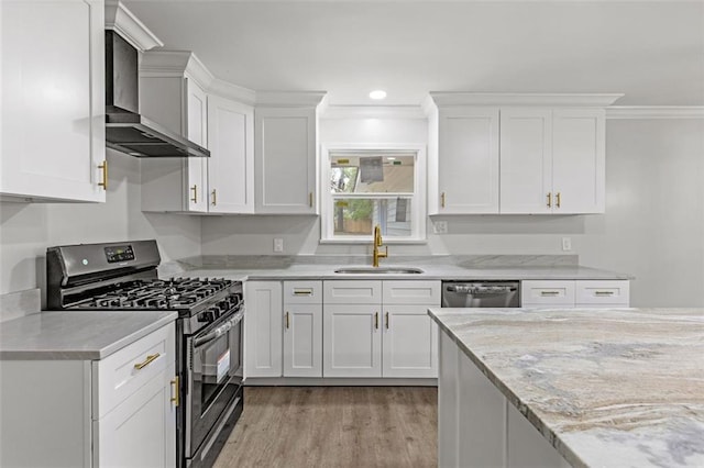 kitchen featuring sink, white cabinets, appliances with stainless steel finishes, light hardwood / wood-style flooring, and wall chimney exhaust hood